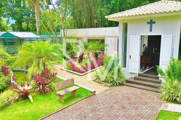 Jardim com lago de carpas e acesso à capela